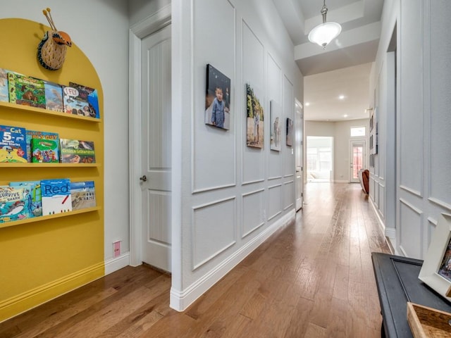 hall with baseboards, recessed lighting, wood-type flooring, and a decorative wall