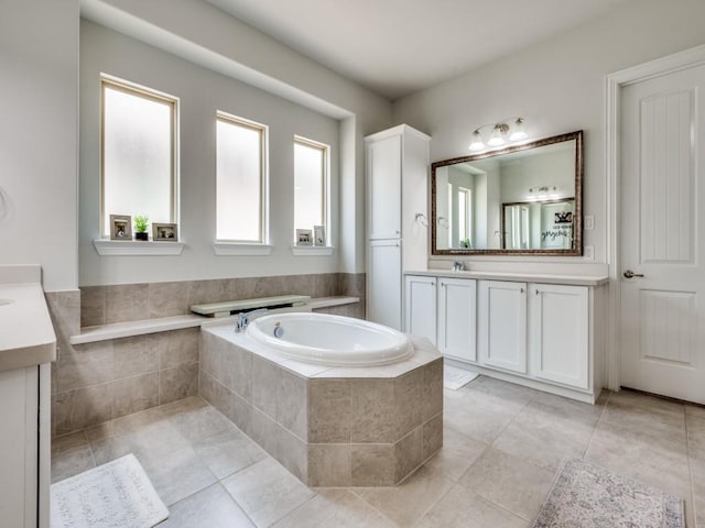 full bath featuring a bath, a sink, two vanities, and tile patterned floors