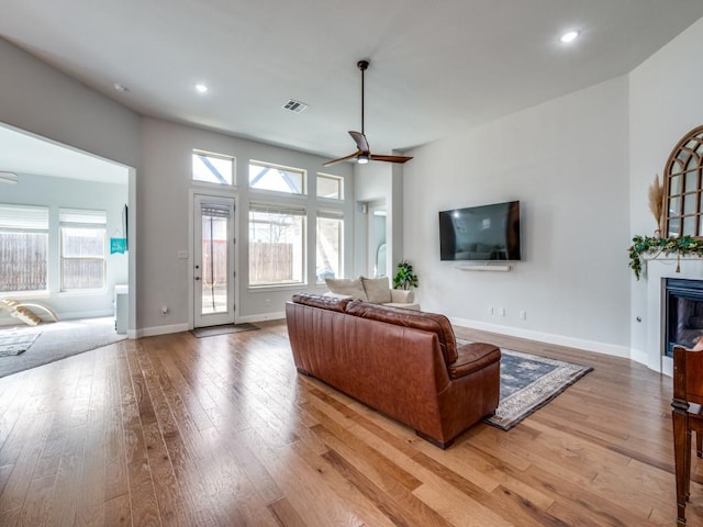 living area featuring plenty of natural light, a glass covered fireplace, and light wood-style floors