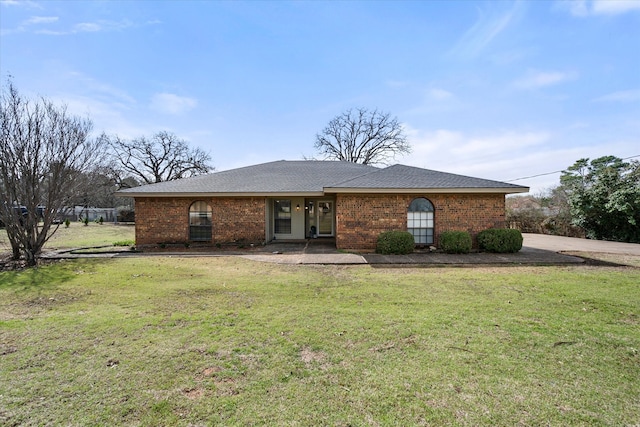 view of front facade featuring brick siding, a front lawn, and roof with shingles