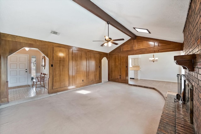 unfurnished living room featuring arched walkways, light carpet, wood walls, visible vents, and beamed ceiling