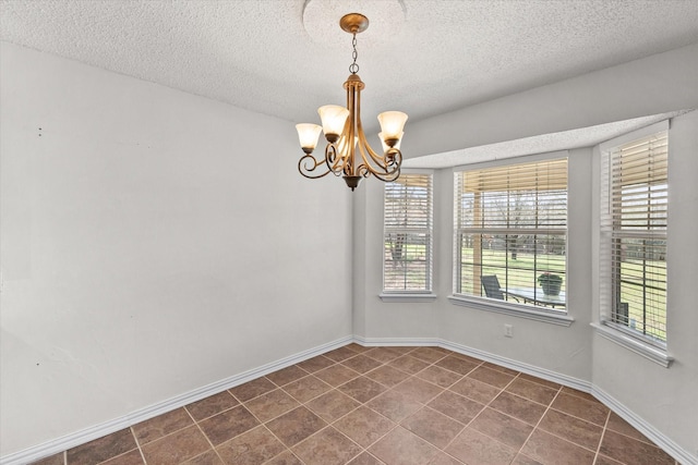 unfurnished room featuring baseboards, dark tile patterned floors, a textured ceiling, and an inviting chandelier