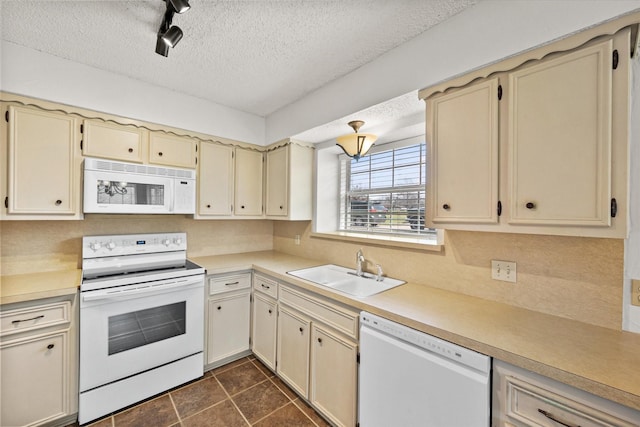 kitchen with cream cabinetry, light countertops, a sink, a textured ceiling, and white appliances