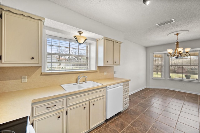 kitchen featuring white dishwasher, a sink, visible vents, cream cabinetry, and plenty of natural light