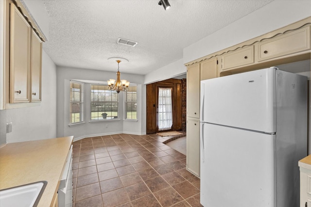 kitchen featuring a chandelier, cream cabinets, a sink, visible vents, and freestanding refrigerator