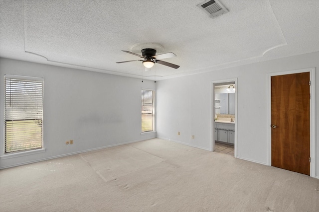 unfurnished bedroom featuring a textured ceiling, connected bathroom, light colored carpet, visible vents, and baseboards