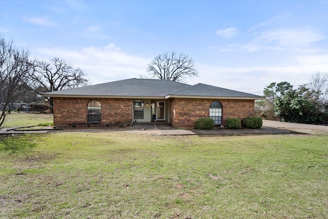 ranch-style home featuring brick siding, roof with shingles, and a front yard