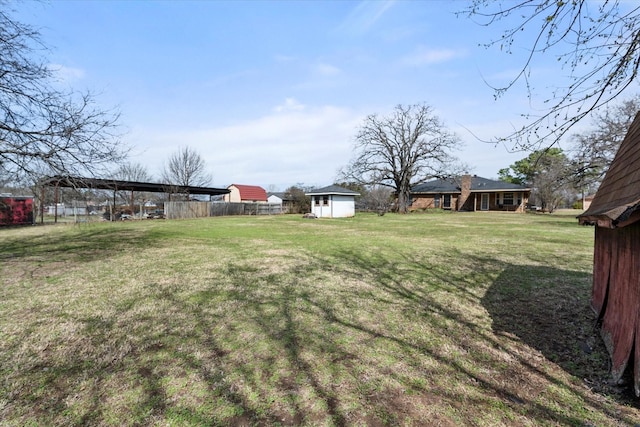 view of yard featuring a shed, fence, and an outdoor structure