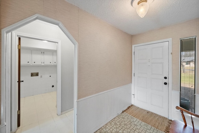 foyer with a wainscoted wall and a textured ceiling