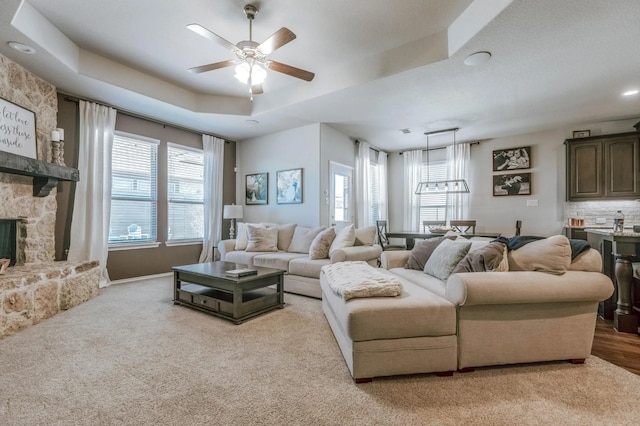 713 Falcon Rd, Argyle, TX 76226 - carpeted living room featuring ceiling fan, a stone fireplace, a tray ceiling, baseboards, and recessed lighting