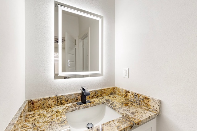 bathroom with a textured wall and vanity