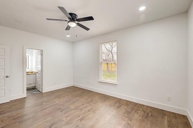 unfurnished bedroom featuring recessed lighting, ensuite bathroom, baseboards, and wood finished floors