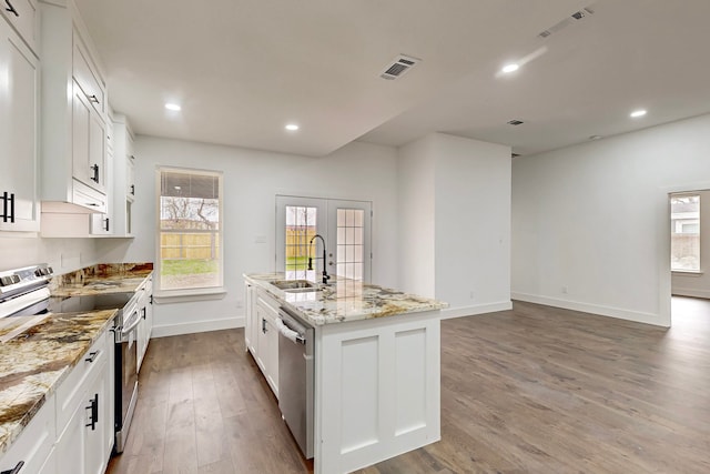 kitchen with stainless steel appliances, wood finished floors, a sink, visible vents, and french doors