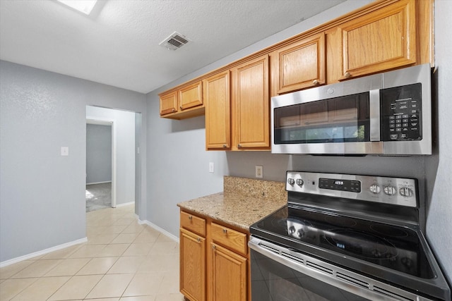 kitchen featuring light tile patterned floors, visible vents, appliances with stainless steel finishes, a textured ceiling, and light stone countertops