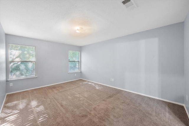 empty room with carpet floors, visible vents, baseboards, and a textured ceiling