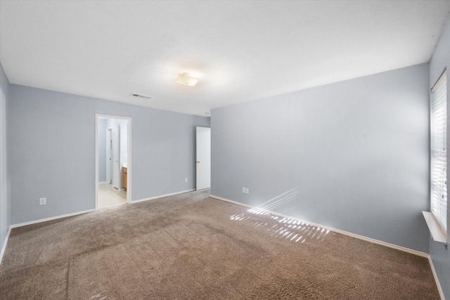 carpeted empty room with visible vents and baseboards