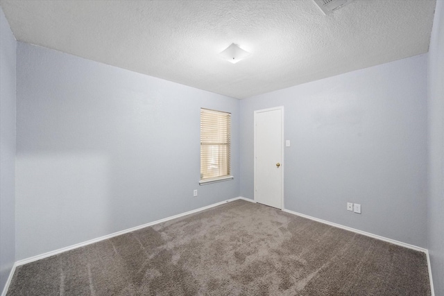 spare room with a textured ceiling, carpet flooring, and baseboards