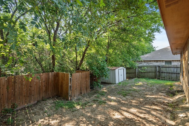 view of yard featuring a shed, a fenced backyard, and an outbuilding