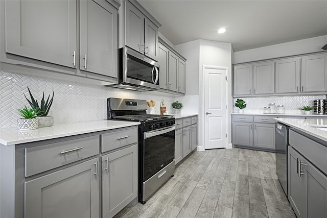 kitchen featuring stainless steel appliances, gray cabinetry, light wood-style flooring, and light countertops