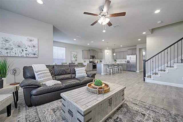 living room with stairway, visible vents, recessed lighting, ceiling fan, and light wood-type flooring