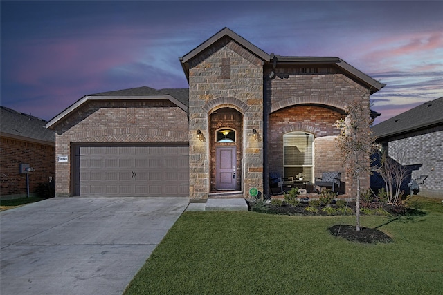 french country home featuring a front lawn, concrete driveway, a garage, stone siding, and brick siding