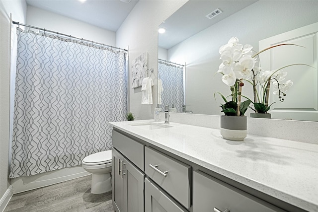 bathroom featuring visible vents, toilet, wood finished floors, shower / bath combination with curtain, and vanity