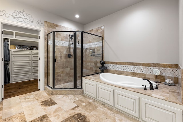 full bath featuring a shower stall, a walk in closet, and a bath