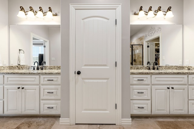 full bathroom with a sink, a shower stall, a closet, and two vanities