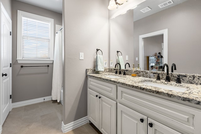 full bath with double vanity, a sink, and visible vents