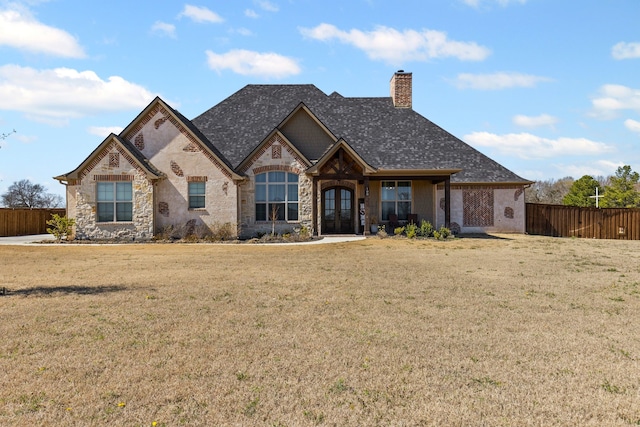 view of front of property featuring a shingled roof, fence, french doors, a front lawn, and a chimney