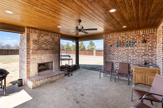 view of patio / terrace featuring ceiling fan, fence, and an outdoor stone fireplace