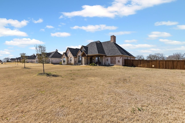 view of front of home featuring a chimney, a front yard, and fence