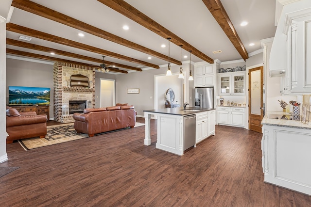 kitchen with white cabinets, dark wood-style floors, open floor plan, stainless steel appliances, and a sink