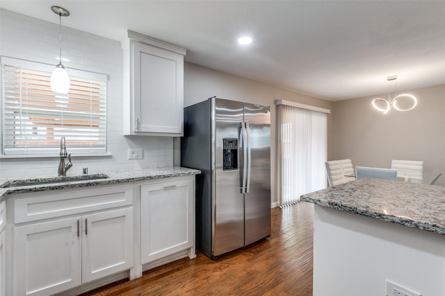 kitchen featuring decorative backsplash, stainless steel fridge with ice dispenser, dark wood-type flooring, decorative light fixtures, and a sink