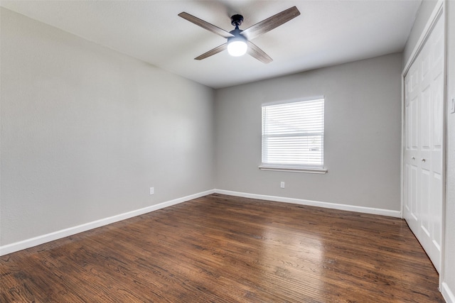 unfurnished bedroom featuring dark wood-type flooring, a closet, and baseboards