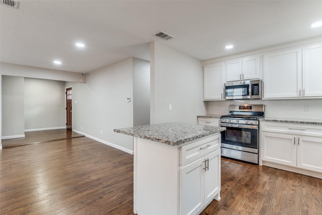 kitchen featuring visible vents, a kitchen island, appliances with stainless steel finishes, dark wood-style flooring, and backsplash