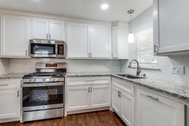 kitchen featuring stainless steel appliances, white cabinetry, a sink, and dark wood-type flooring