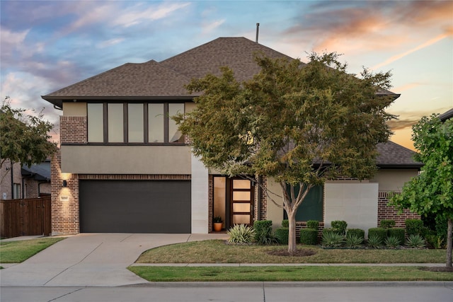 view of front of property with brick siding, fence, roof with shingles, stucco siding, and driveway