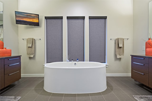 bathroom featuring tile patterned floors, a freestanding tub, baseboards, and vanity