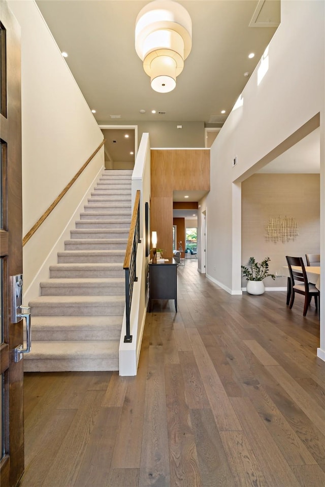 interior space featuring hardwood / wood-style floors, recessed lighting, baseboards, and a towering ceiling