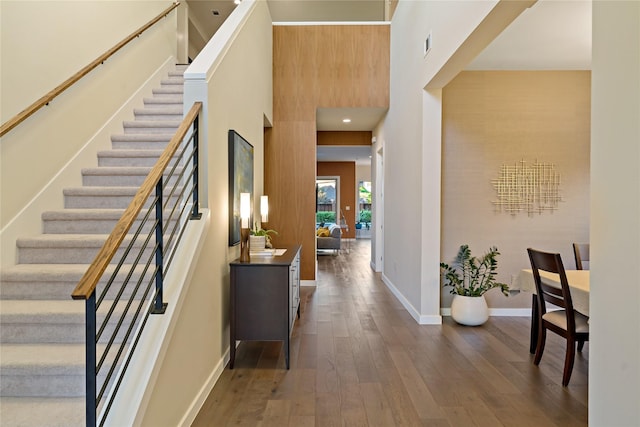 entryway with visible vents, wood-type flooring, baseboards, a towering ceiling, and stairs