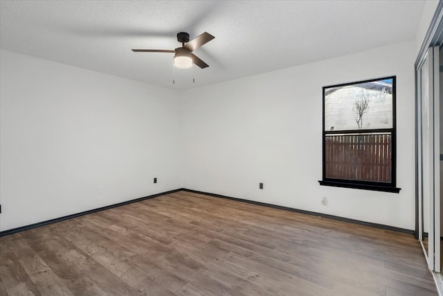 empty room featuring baseboards, a textured ceiling, wood finished floors, and a ceiling fan