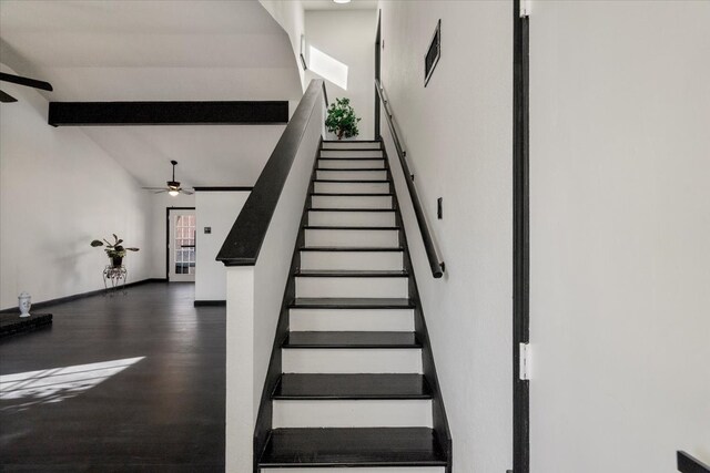 stairway featuring baseboards, a ceiling fan, wood finished floors, and vaulted ceiling with beams