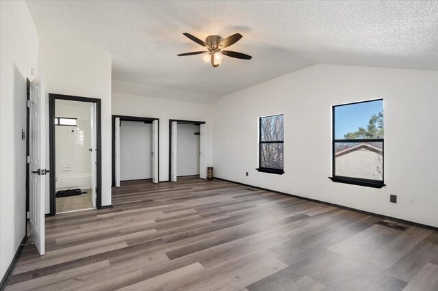 unfurnished bedroom with a ceiling fan, wood finished floors, visible vents, lofted ceiling, and a textured ceiling