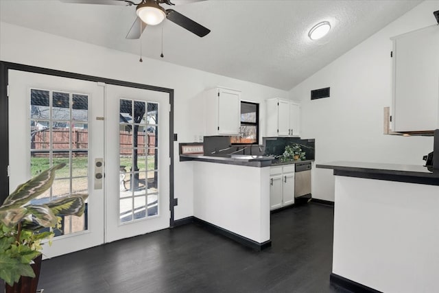 kitchen featuring stainless steel dishwasher, dark countertops, white cabinetry, french doors, and vaulted ceiling