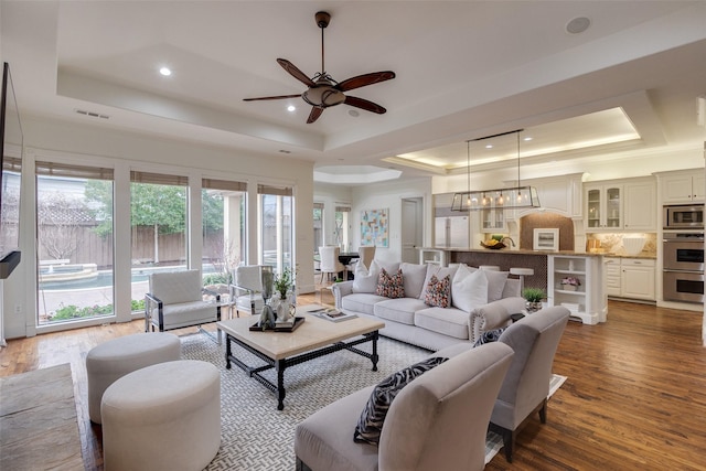 living room with wood finished floors, a raised ceiling, a ceiling fan, and recessed lighting