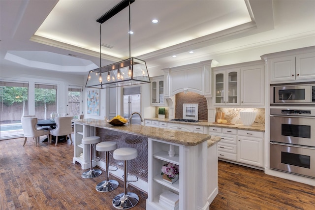 kitchen featuring built in appliances, dark wood-type flooring, white cabinets, open shelves, and a tray ceiling