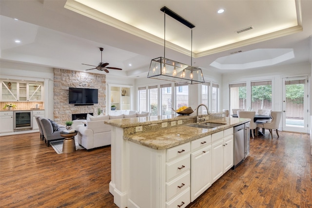 kitchen with a raised ceiling, wine cooler, a sink, and visible vents