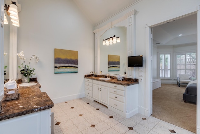 ensuite bathroom with baseboards, tile patterned flooring, vaulted ceiling, crown molding, and vanity