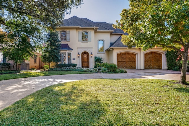 view of front of home with an attached garage, driveway, roof with shingles, stucco siding, and a front yard